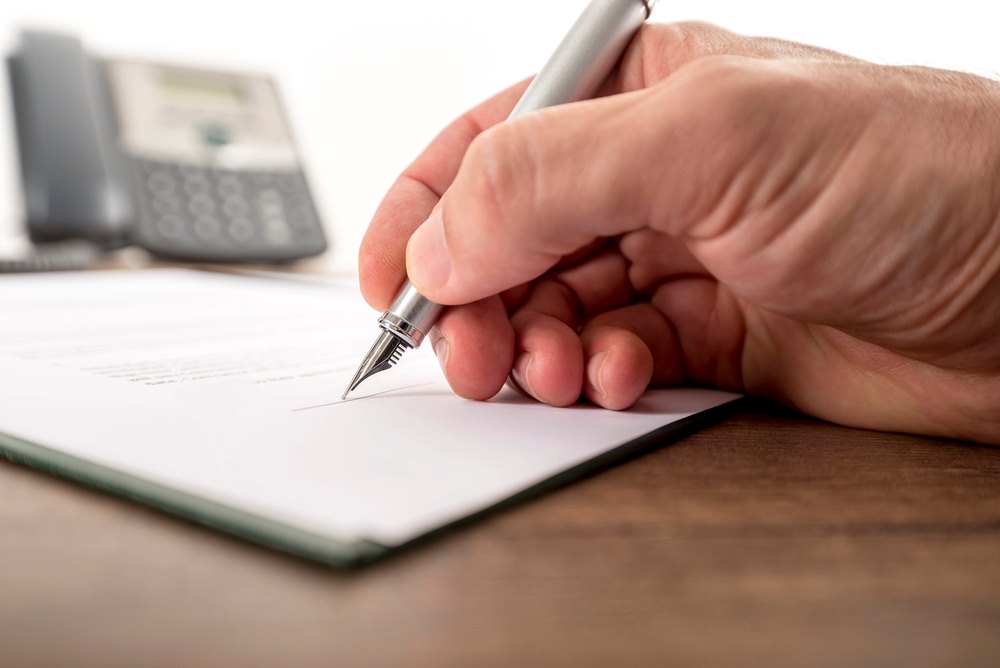 Image of a businessman or lawyer signing important legal documents, featuring 411 Immigration Law and highlighting Enrollment in a Recognized Institution, ensuring it aligns with the page's context.