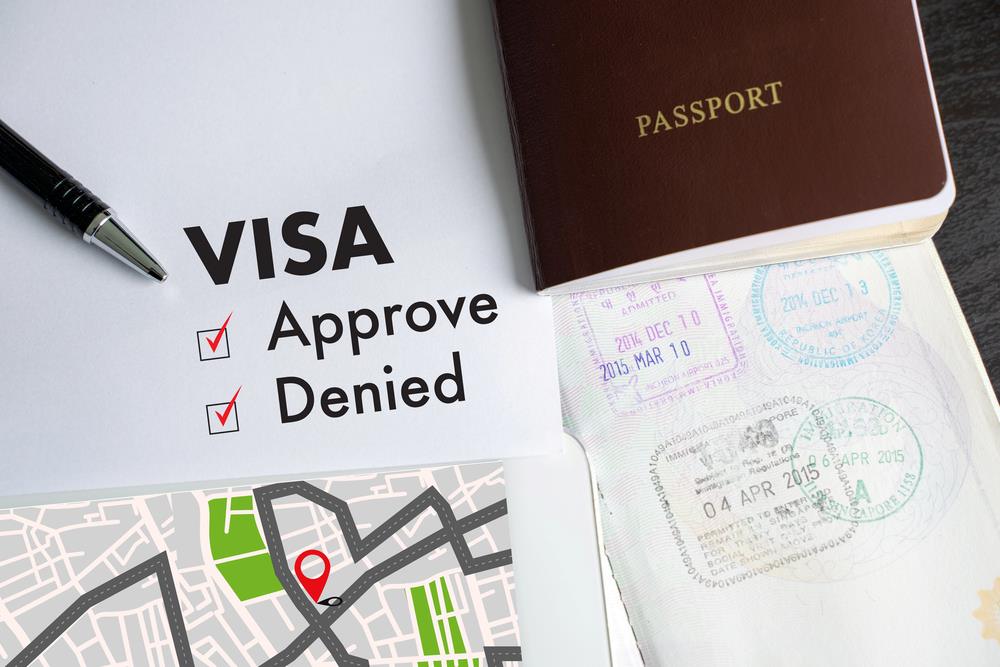Image of a visa and passport with an approved stamp on a document, featuring 411 Immigration Law and highlighting Handling Visitor Visa Denials, ensuring it aligns with the page's context.